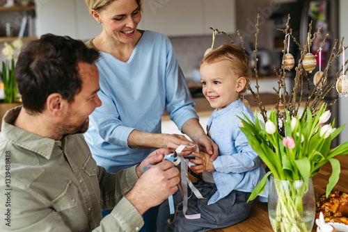 Sticker Parents helping little boy to decorate easter whip from willow branches with ribbons