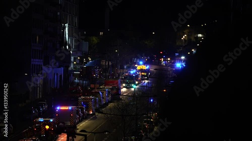 A car accident in Paris at night, with multiple emergency vehicles, including fire trucks and ambulances, responding with flashing lights. 