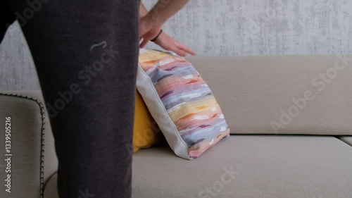Arranging Cushions on Sofa with Hands in Cozy Living Room