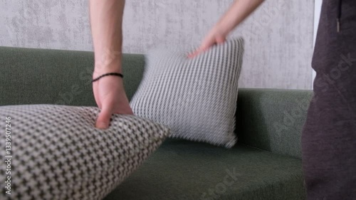 Arranging Cushions on Sofa with Hands in Cozy Living Room