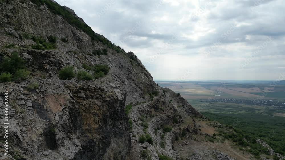 Mountain slope overlooking a valley with fields and a distant town