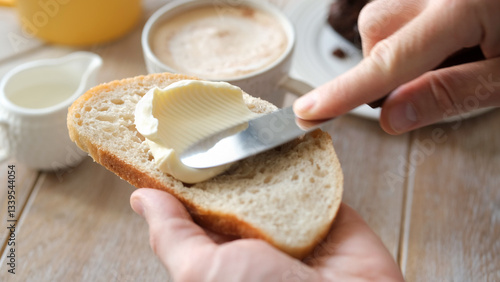 Spreading soft butter on white bread toast, closeup view