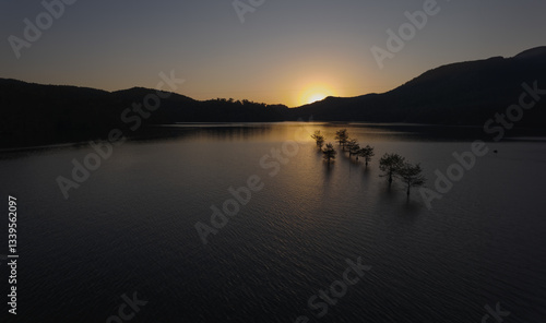 sunset on a lake with small trees in the water