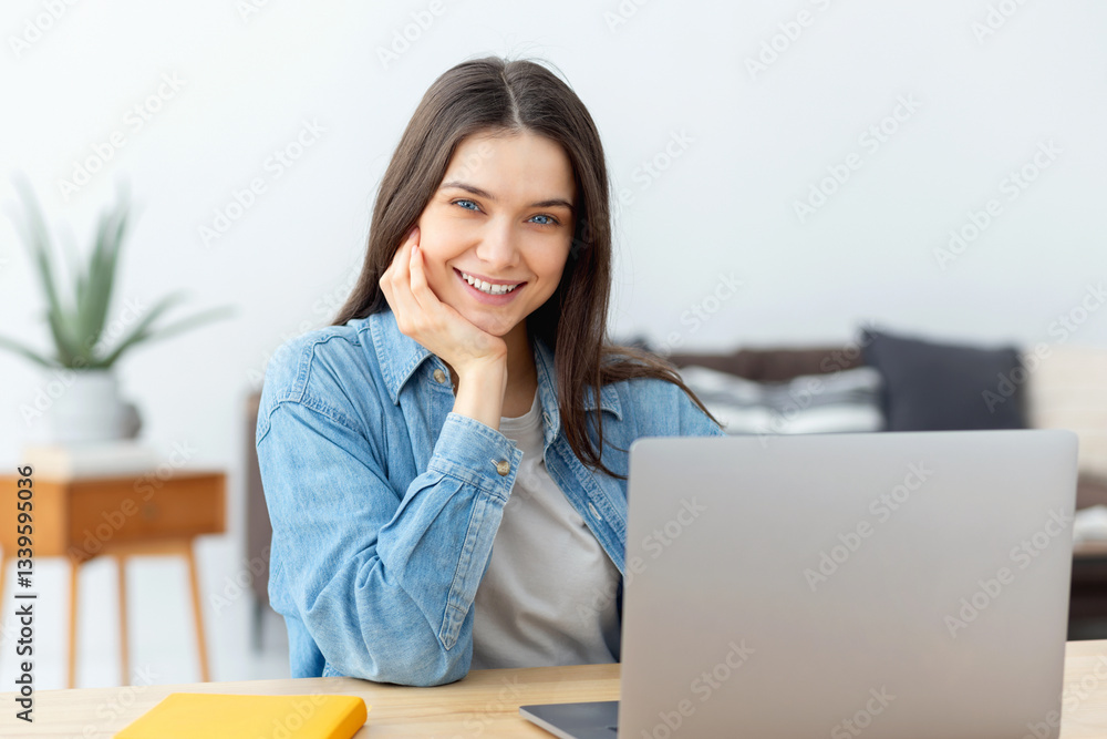 Smiling young woman working on laptop home