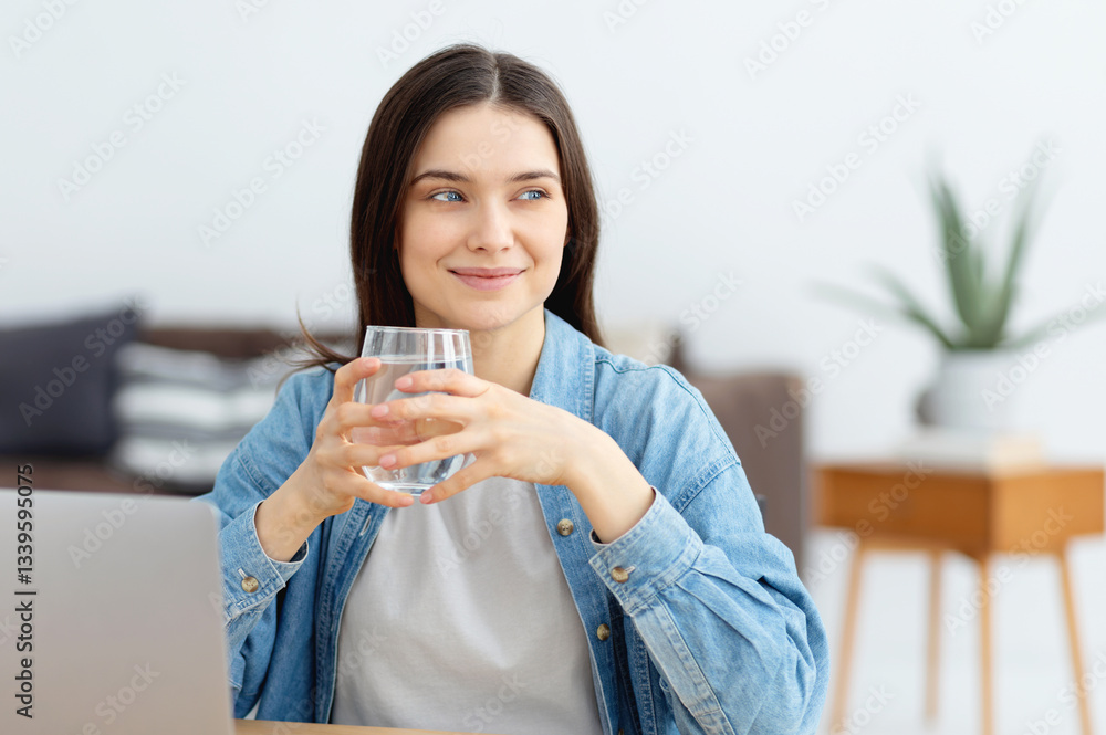 Young woman drinking water at home office