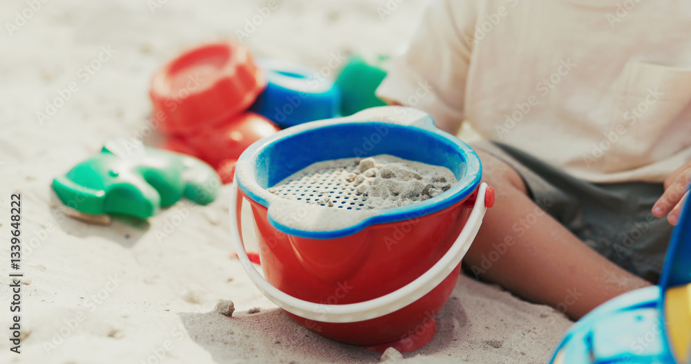 Little boy spends childhood in the backyard, playing in the sandbox, pouring sand from a shovel through a strainer to build castles. Little boy spends childhood in the backyard, playing in the sandbox, pouring sand from a shovel through a strainer to build castles.