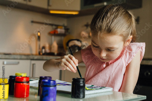 Young girl focused on painting with vibrant watercolors photo