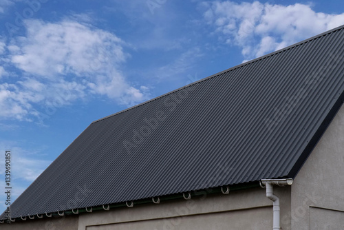 Gray building with wavy metal roof and gutter system