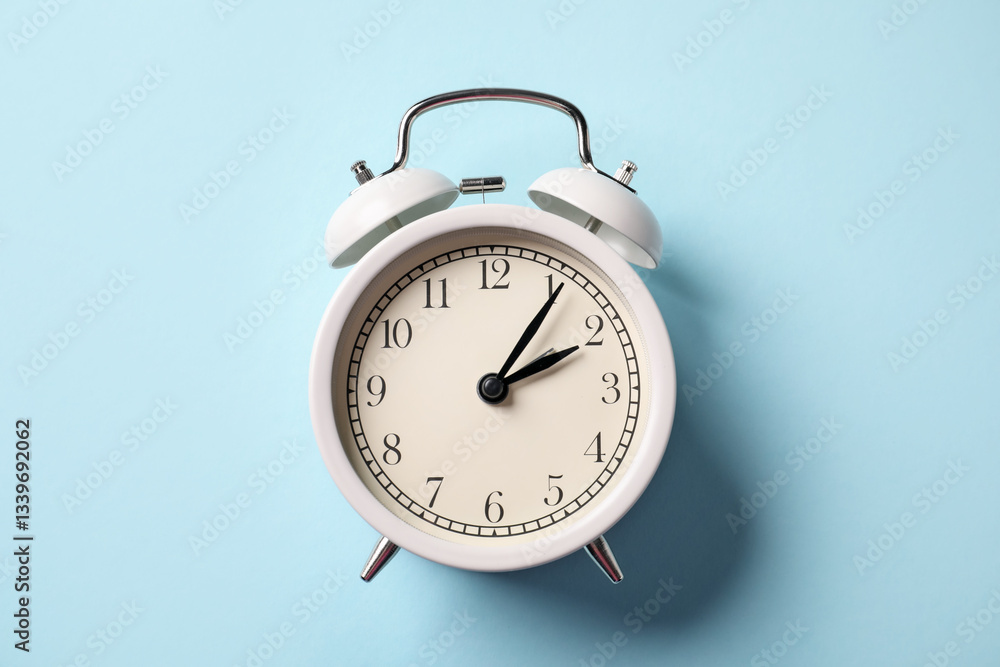 White alarm clock on light blue background, top view White alarm clock on light blue background, top view