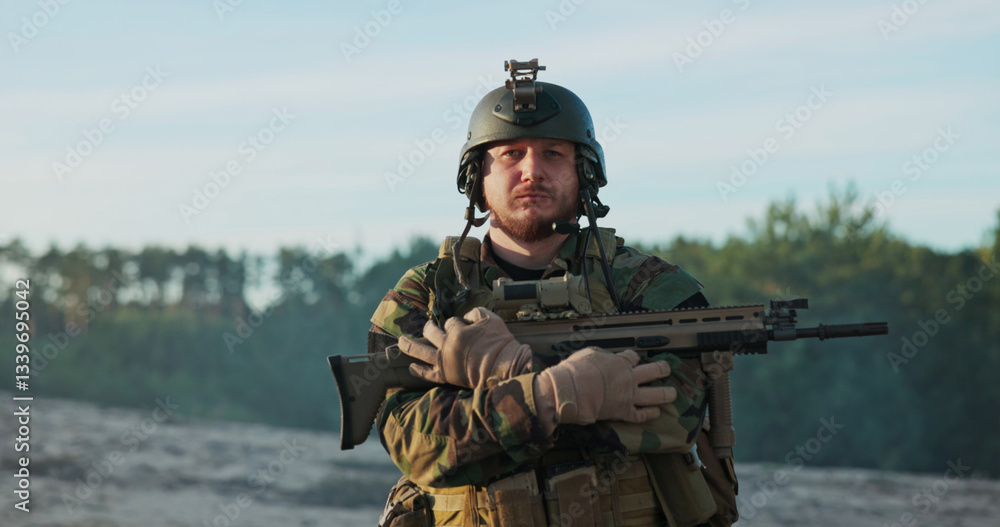 Fototapeta premium A strong and disciplined soldier, dressed in a moro uniform with a helmet and gear belt, stares into the camera, gripping his gun and crossing his arms over his chest in a symbol of duty.