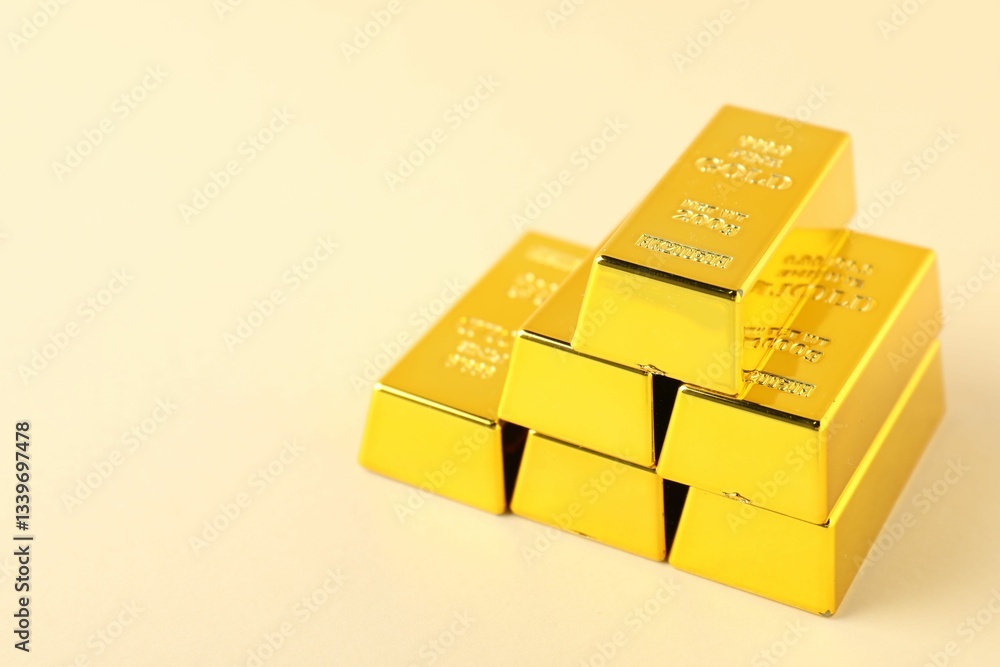 Shiny gold bars on beige background, closeup. Space for text Shiny gold bars on beige background, closeup. Space for text