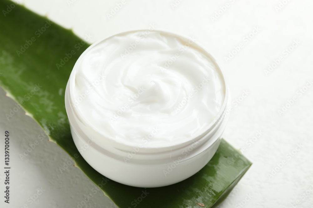 Moisturizing cream with extract of aloe vera and cut leaf on white textured background, closeup Moisturizing cream with extract of aloe vera and cut leaf on white textured background, closeup
