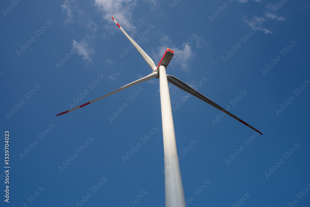 A wind turbine with a blue sky and clouds. Concept of clean energy. A wind turbine with a blue sky and clouds. Concept of clean energy.