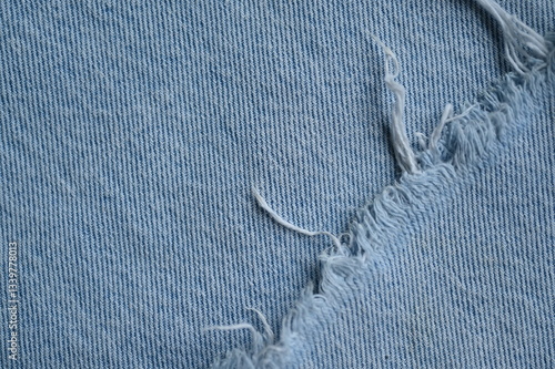 torn light grey denim surface, denim fringe , hole macro texture of blue denim, torn blue denim texture as background photo close up from above	
