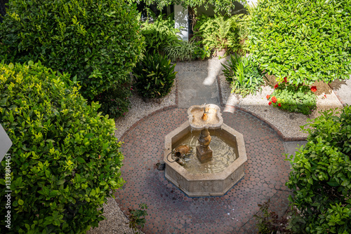 A fountain in a shaded tiled courtyard in Morocco with lush green orange trees surrounding it. Courtyards in private homes, called roads, is often the central feature, and are serene, private oases.