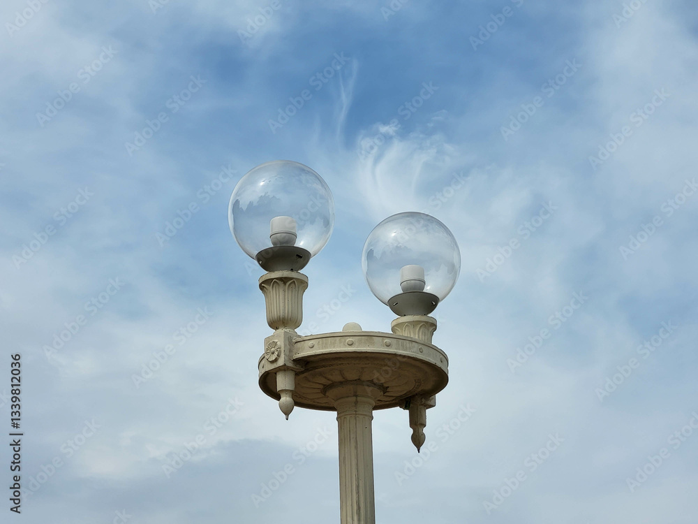 Round transparent street lights against a blue sky with feathery clouds. Round transparent street lights against a blue sky with feathery clouds.