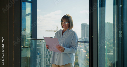 Experienced businesswoman reviewing documents on a balcony with a cityscape in the background, symbolizing focus and professional dedication in a modern corporate setting Free Download Experienced businesswoman reviewing documents on a balcony with a cityscape in the background, symbolizing focus and professional dedication in a modern corporate setting - GFXLoad