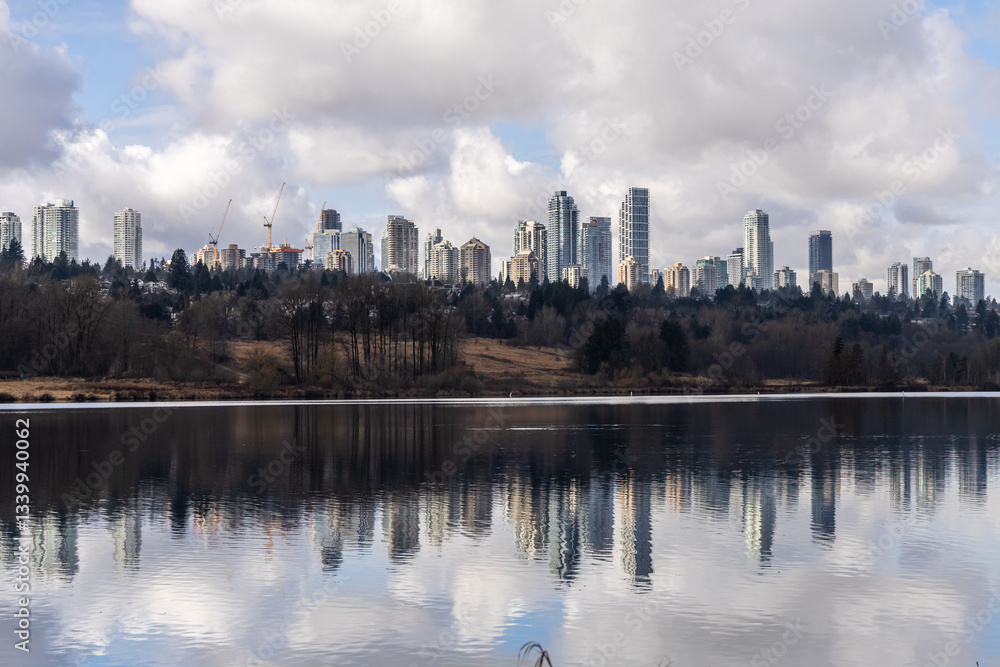 Fototapeta premium Reflection of Burnaby Skyline Over Deer Lake Under Cloudy Sky