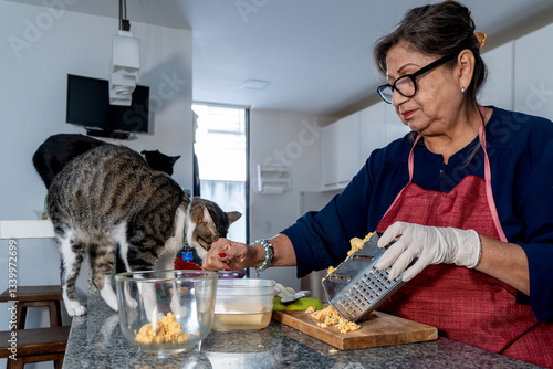 Wallpaper Mural Senior woman grating food in kitchen with curious cats watching Torontodigital.ca