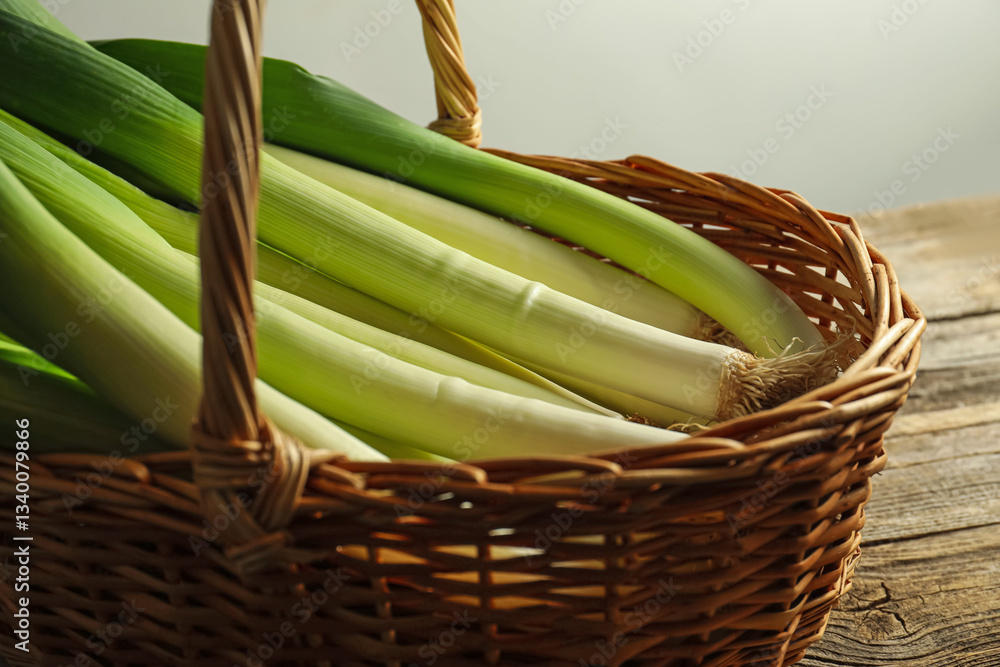 Fresh leeks in wicker basket on wooden table, closeup Fresh leeks in wicker basket on wooden table, closeup