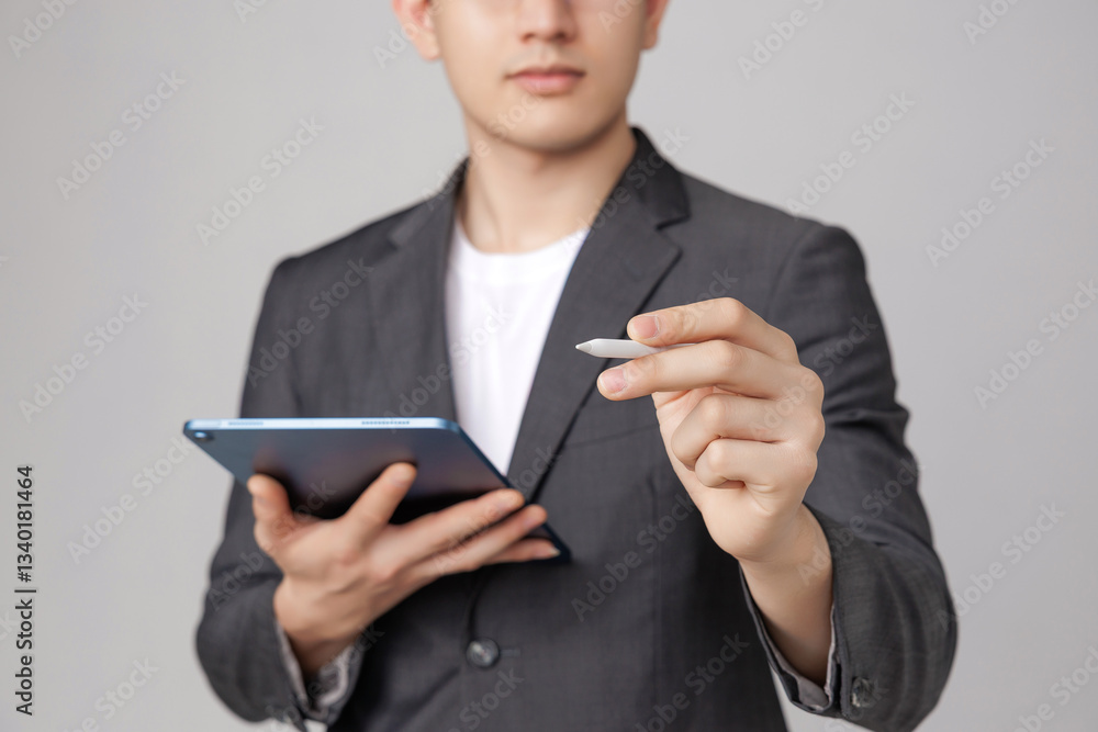 Close up hand of Young Asian confident man wearing glasses in grey suit holding tablet working online marketing or chat with customer. Business planning manager. Close up hand of Young Asian confident man wearing glasses in grey suit holding tablet working online marketing or chat with customer. Business planning manager.