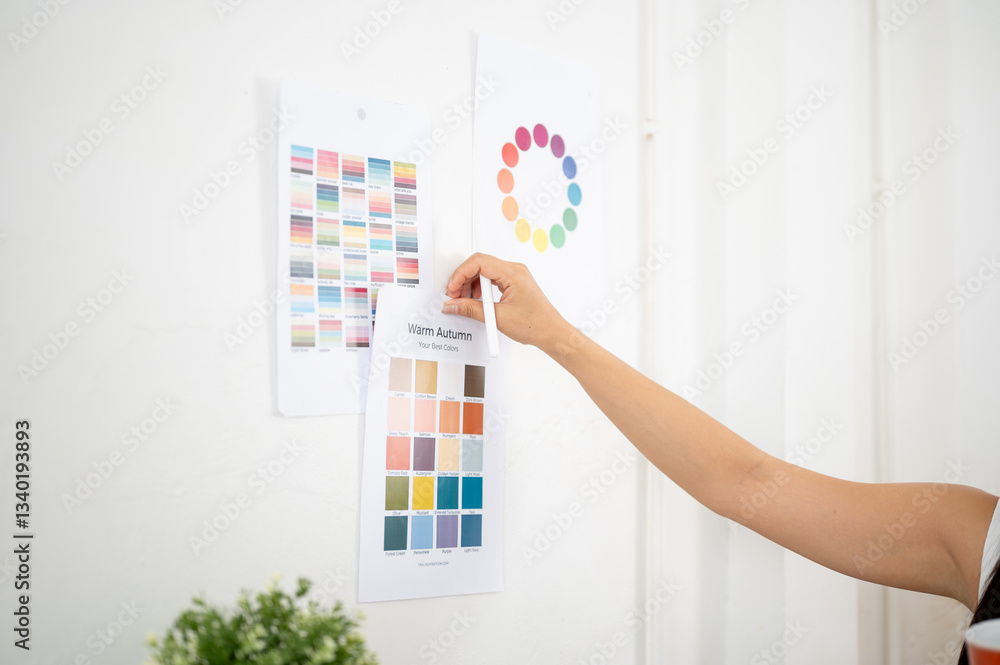 Close up of a hand sticking or taking off a printed color palette on the wall, Designer in office. Close up of a hand sticking or taking off a printed color palette on the wall, Designer in office.