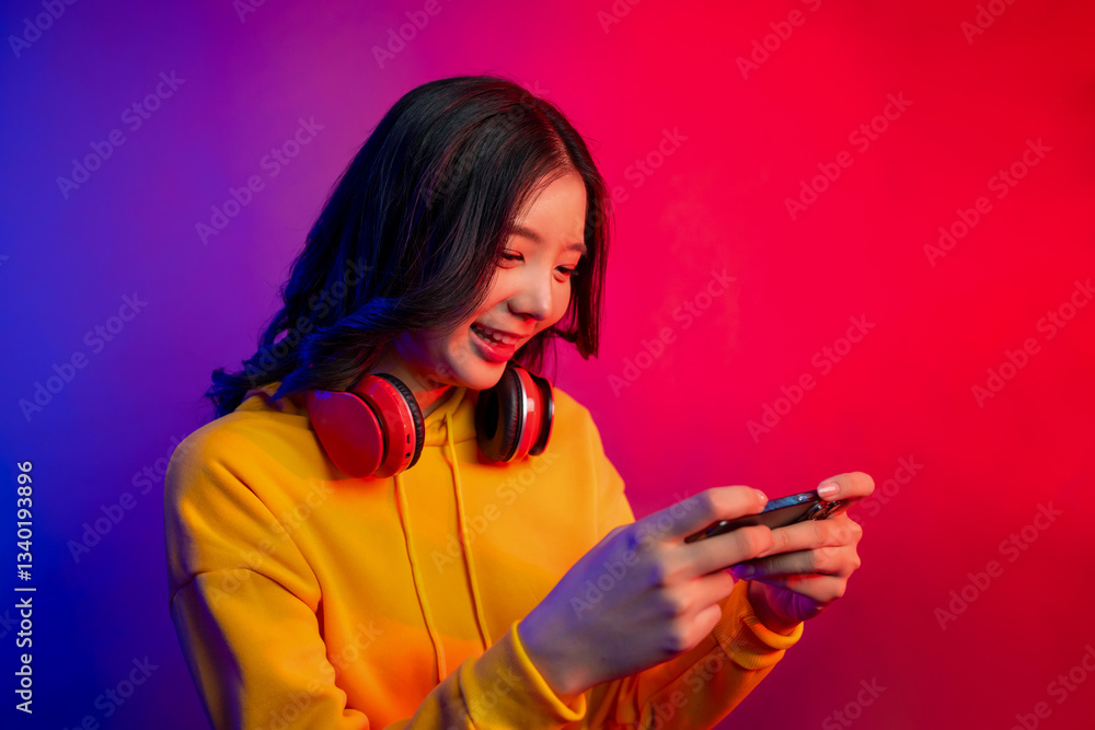 Asian young beautiful woman playing game on smartphone in neon background. Asian young beautiful woman playing game on smartphone in neon background.