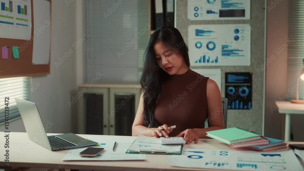 Asian businesswoman using calculator at office desk Asian businesswoman using calculator at office desk