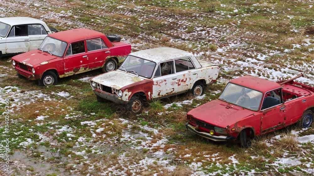 Old, Russian deteriorating vehicles from the Soviet era rest in an open, drone Old, Russian deteriorating vehicles from the Soviet era rest in an open, drone