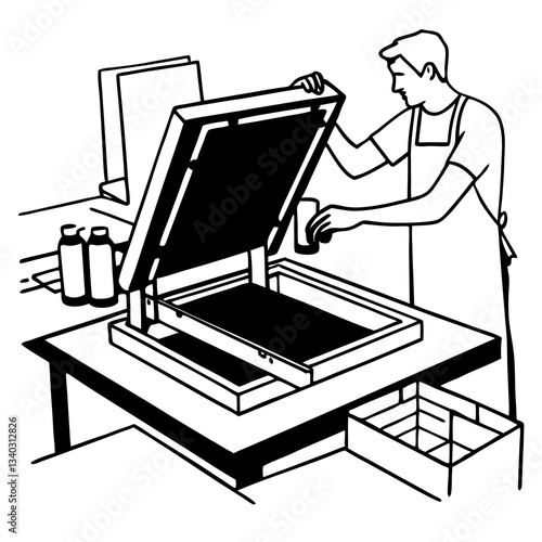 Male worker pressing ink on frame while using the printing machine in a workshop
