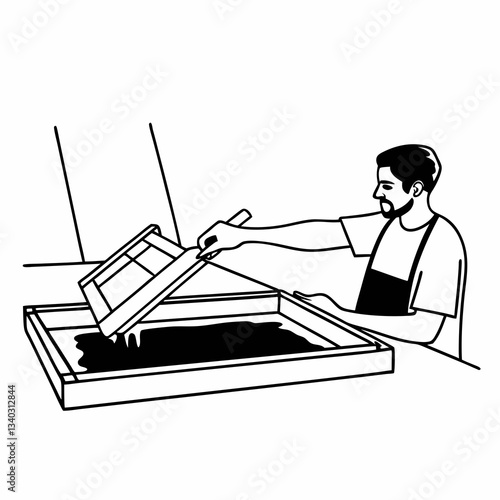 Male worker pressing ink on frame while using the printing machine in a workshop
