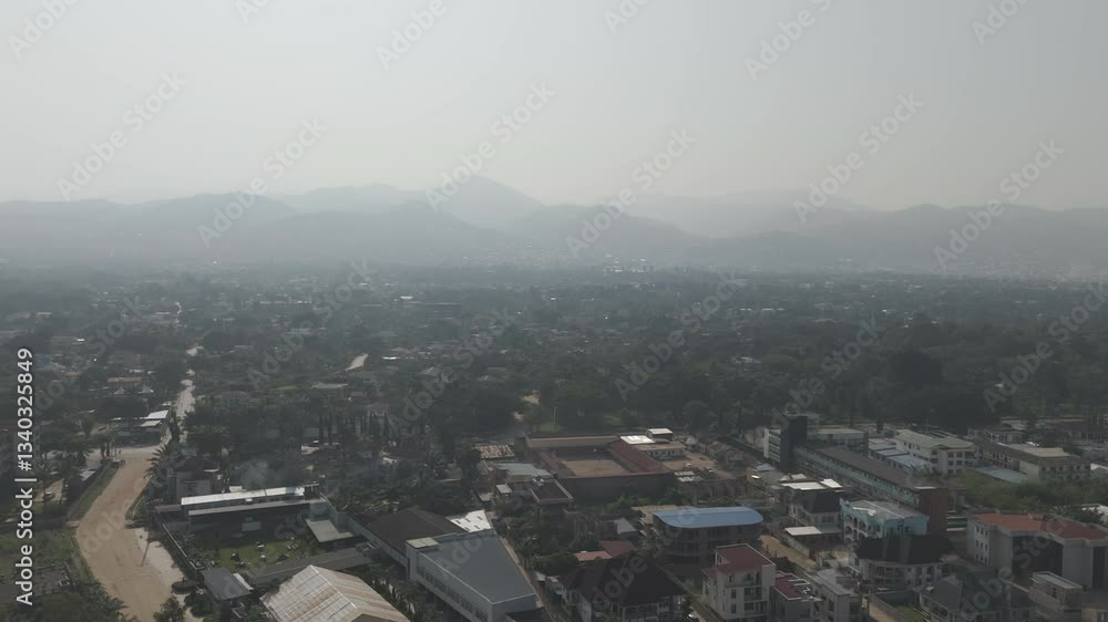 Backwards drone shot above Bujumbura Burundi Africa looking over the houses near lake Tanganyika looking over the mountains with mist and pollution in the air LOG Backwards drone shot above Bujumbura Burundi Africa looking over the houses near lake Tanganyika looking over the mountains with mist and pollution in the air LOG
