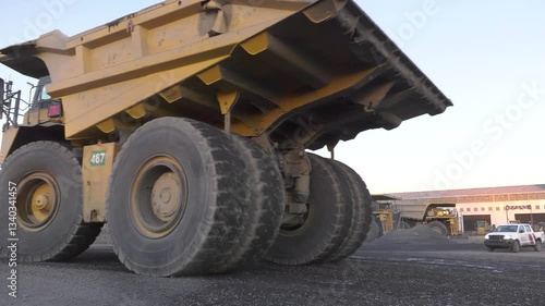 mining trucks construction machinery passing by at sunset at a diamond mine , pickup truck in the background