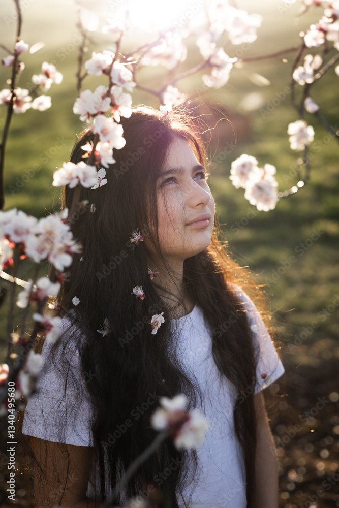 Fototapeta premium long-haired teen girl portraits in a blooming cherry garden