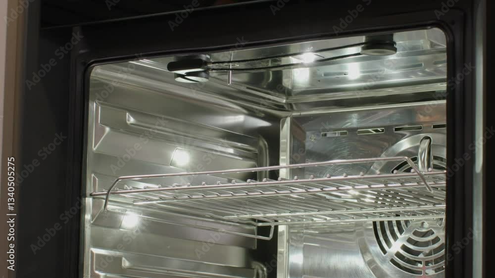 Close up of hands placing a baking dish inside a modern oven with metal racks Close up of hands placing a baking dish inside a modern oven with metal racks