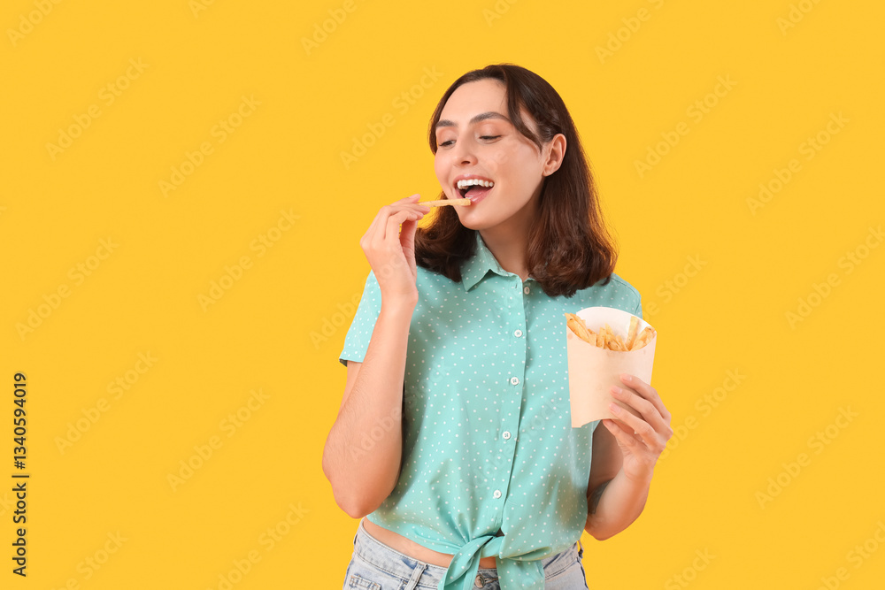 Young woman eating french fries on yellow background Young woman eating french fries on yellow background