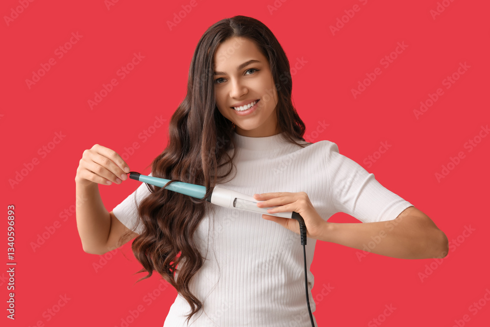 Beautiful young woman with curling iron on red background Beautiful young woman with curling iron on red background