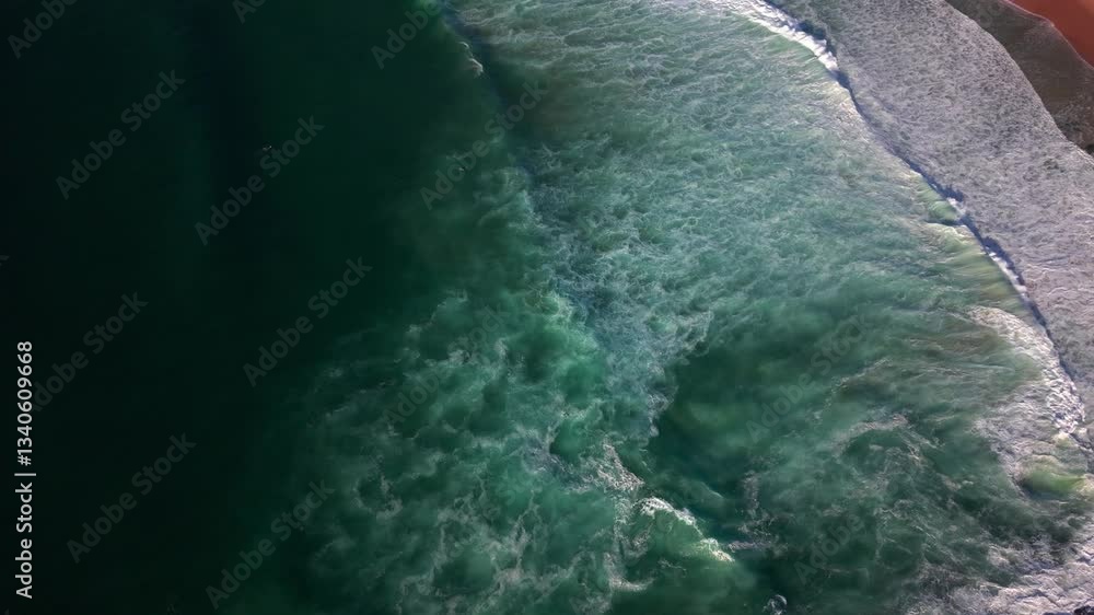 Powerful ocean waves crash onto the shore in Newcastle, Australia, creating white foam and turbulence, green and deep blue seafoam at sunrise Powerful ocean waves crash onto the shore in Newcastle, Australia, creating white foam and turbulence, green and deep blue seafoam at sunrise