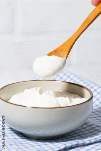 thick greek yogurt in a bowl and a spoon with yogurt, vertical closeup