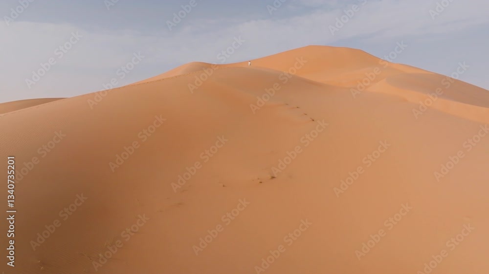 A lone figure standing on the highest dune in the Empty Quarters, Oman