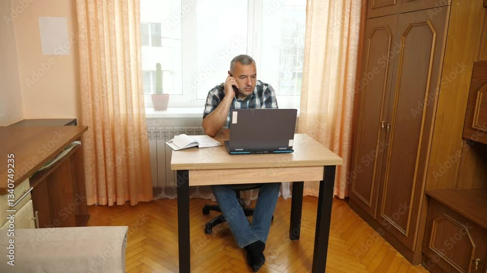 A man works while sitting at a table with a laptop. A man works while sitting at a table with a laptop.
