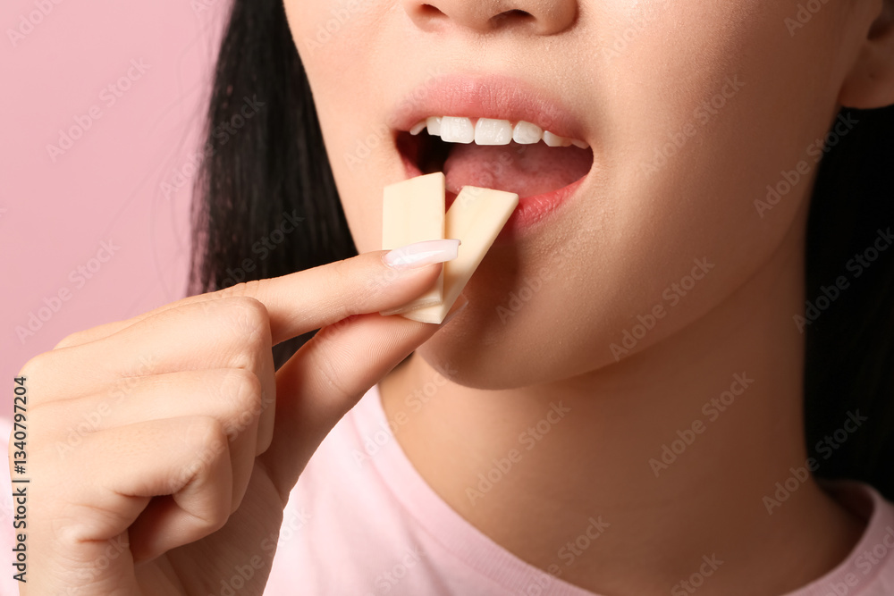 Pretty young Asian woman with open mouth holding chewing gums on pink background, closeup Pretty young Asian woman with open mouth holding chewing gums on pink background, closeup