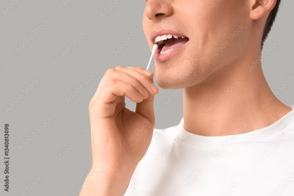 Young man with cotton bud on grey background, closeup Young man with cotton bud on grey background, closeup