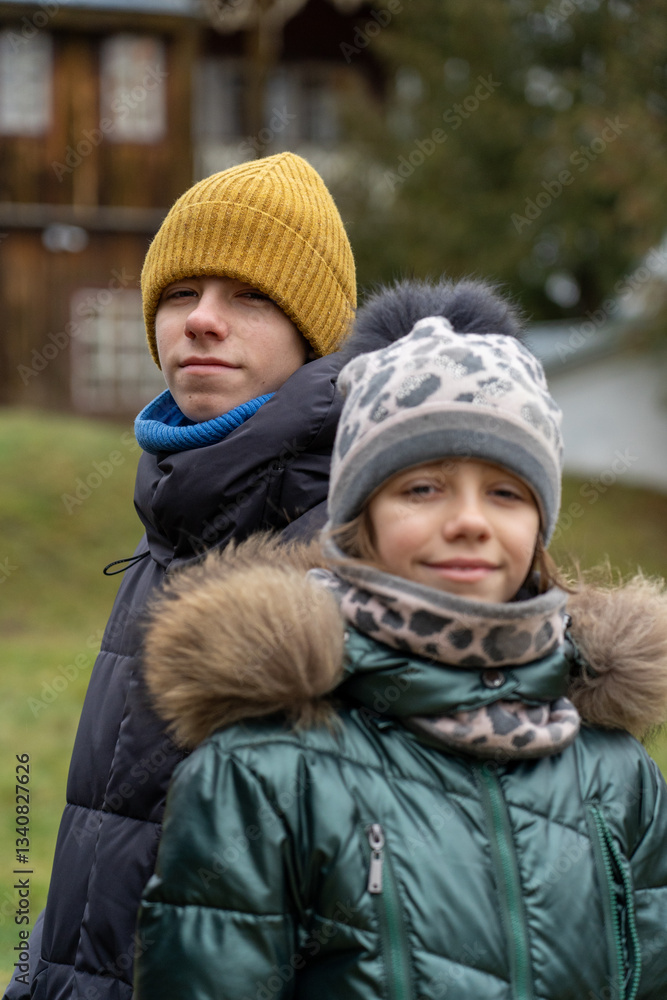 Fototapeta premium Winter Portrait: Two children bundled in warm coats and hats outdoor, cold weather season apparel, smiling, cheerful