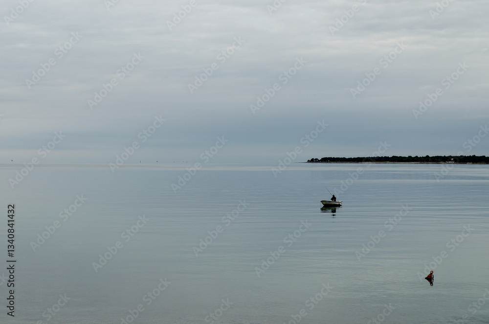 Solitary fisherman in a boat on a calm ocean Solitary fisherman in a boat on a calm ocean