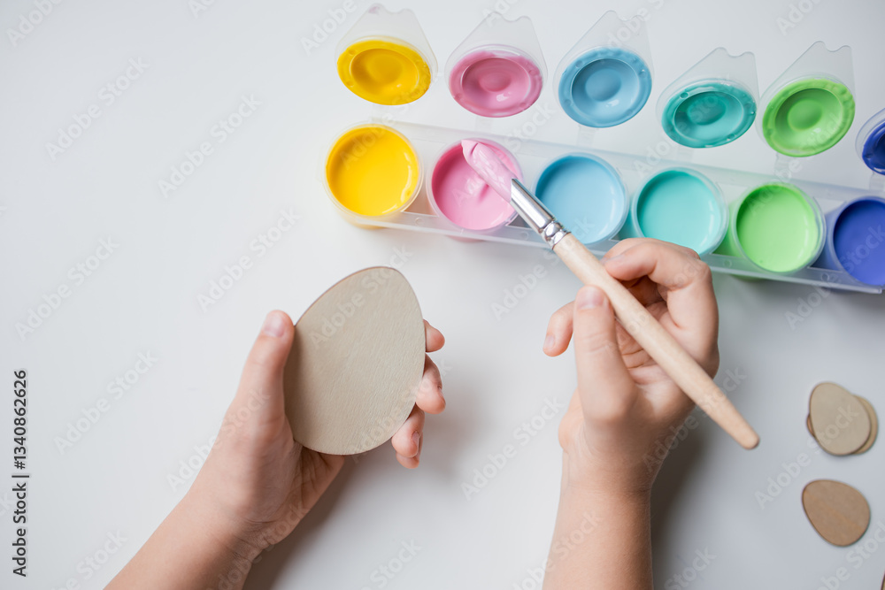 Child painting Easter egg with pastel colors on white background Child painting Easter egg with pastel colors on white background