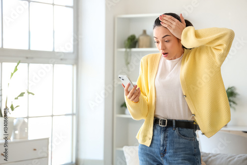 Shocked young woman using m...