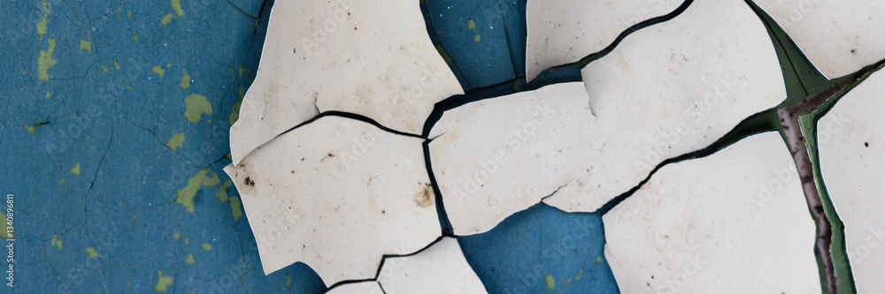 Peeling paint on the wall. Panorama of a concrete wall with old cracked flaking paint. Weathered rough painted surface with patterns of cracks and peeling. Panoramic texture for background and design.