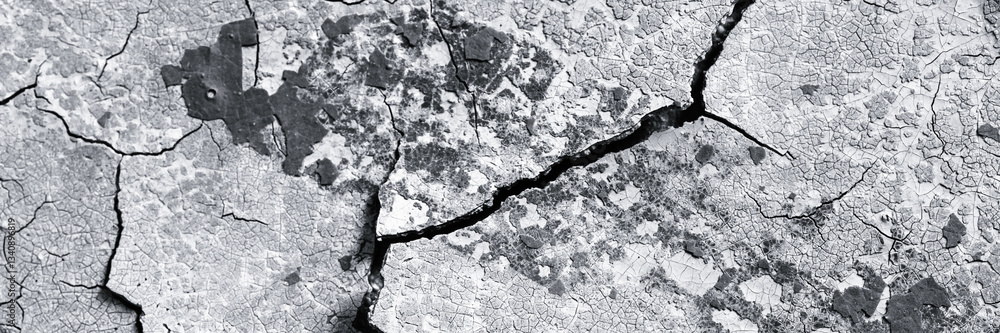 Peeling paint on the wall. Panorama of a concrete wall with old cracked flaking paint. Weathered rough painted surface with patterns of cracks and peeling. Wide panoramic grunge texture for background