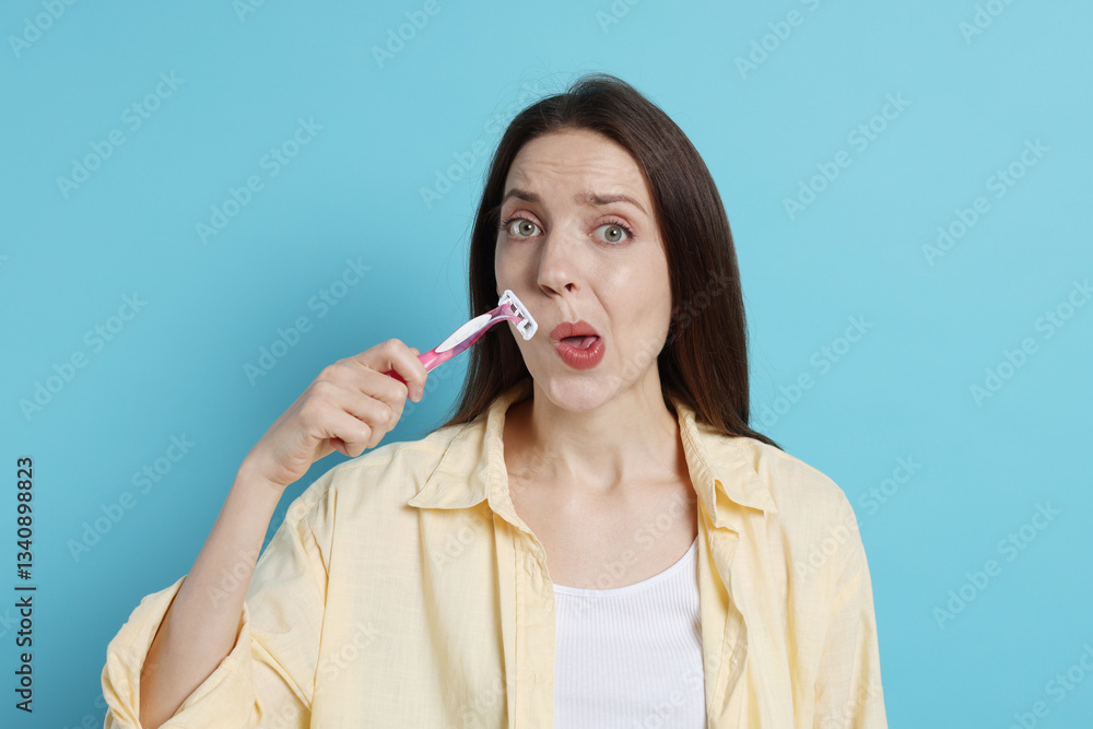 Woman shaving her mustache with razor on light blue background Woman shaving her mustache with razor on light blue background